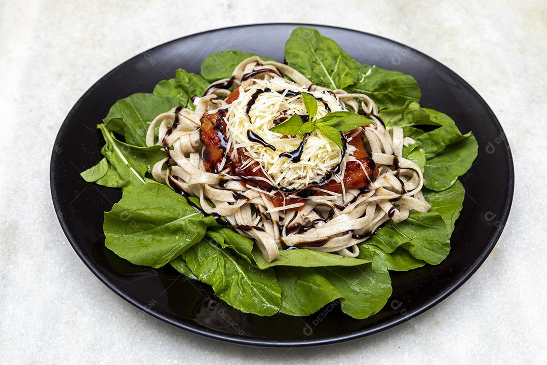 massa de massa integral com queijo parmesão, folhas verdes de rúcula