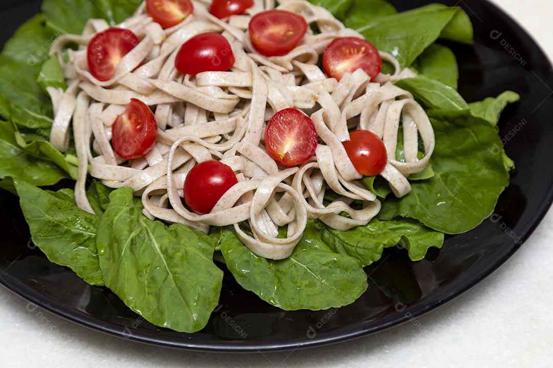Massa integral com folhas verdes de rúcula e tomate cereja