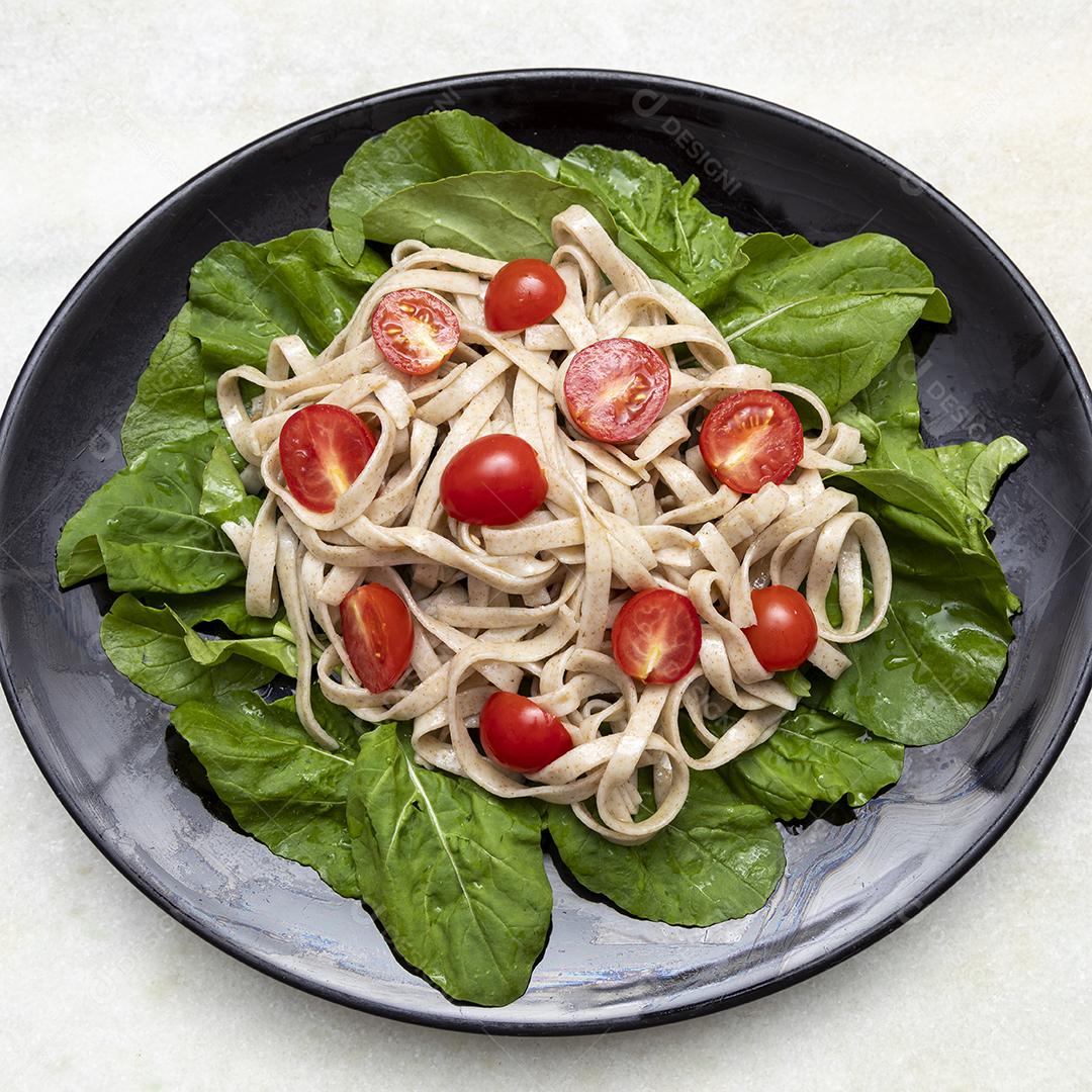 Massa integral com folhas verdes de rúcula e tomate cereja