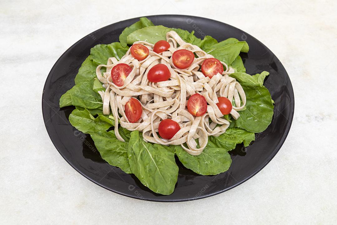 Massa integral com folhas verdes de rúcula e tomate cereja