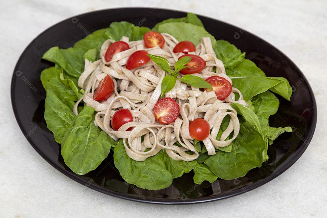 Massa integral com folhas verdes de rúcula e tomate cereja