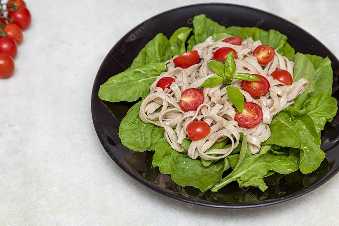 Massa integral com folhas verdes de rúcula e tomate cereja