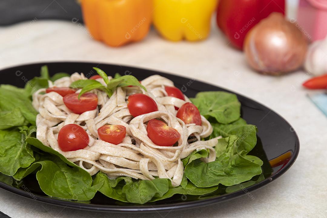 Massa integral com folhas verdes de rúcula e tomate cereja