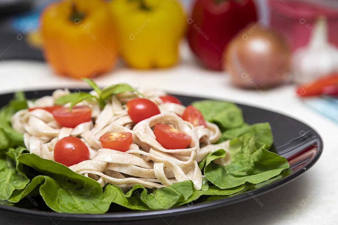 Massa integral com folhas verdes de rúcula e tomate cereja