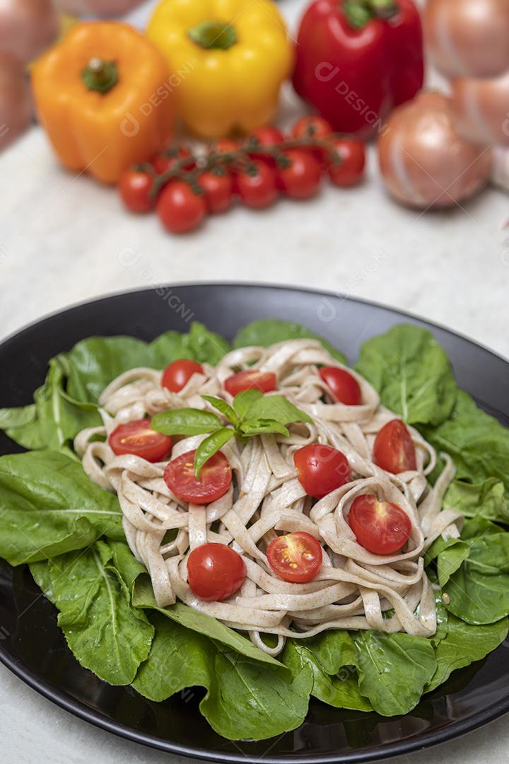 Massa integral com folhas verdes de rúcula e tomate cereja