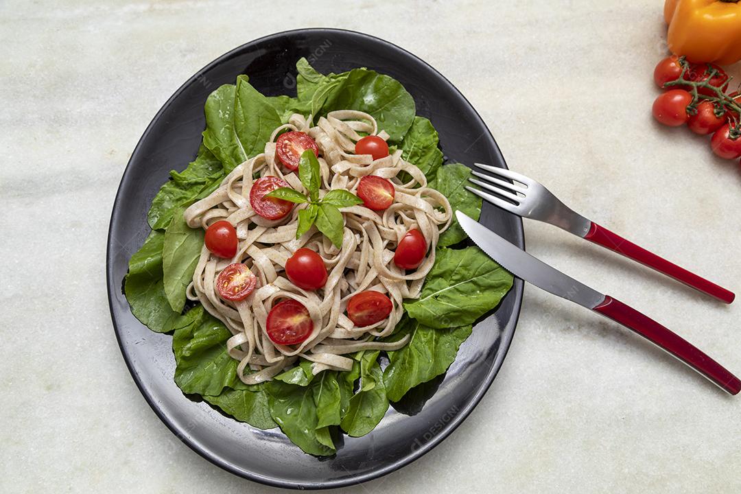Massa integral com folhas verdes de rúcula e tomate cereja