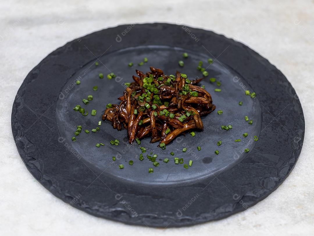 Cogumelo Shimeji servido com cebolinha no prato de pedra preta. Tipica JPG