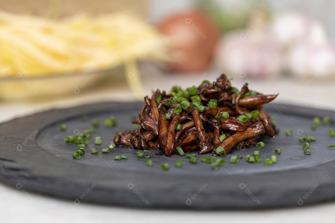 Cogumelo Shimeji servido com cebolinha no prato de pedra preta. Tipica JPG