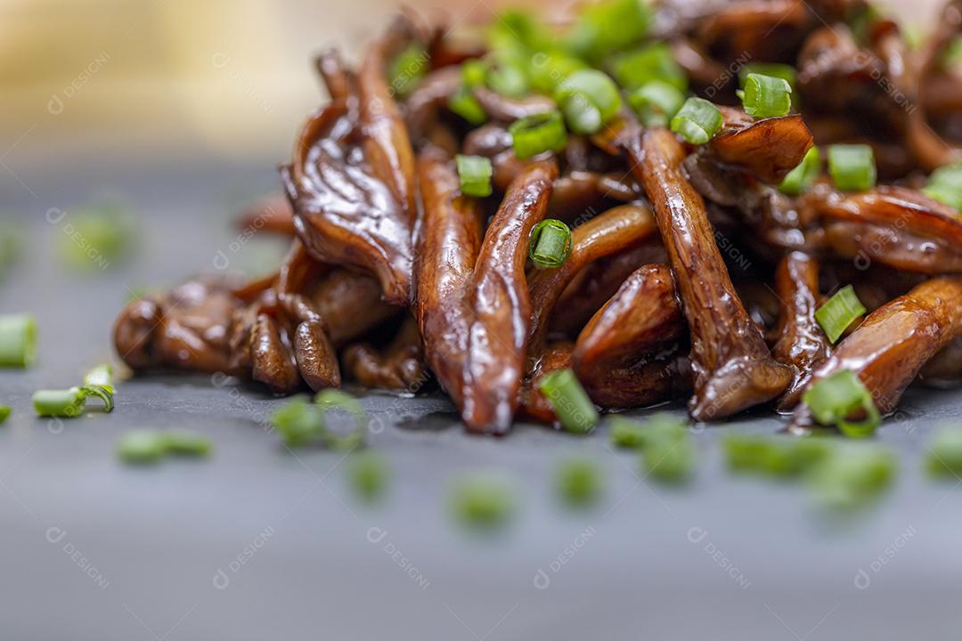 Cogumelo Shimeji servido com cebolinha no prato de pedra preta. Tipica JPG