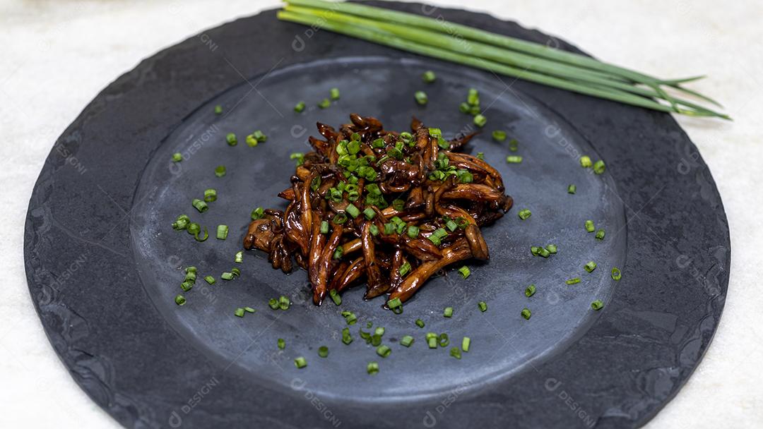 Cogumelo Shimeji servido com cebolinha no prato de pedra preta. Tipica JPG