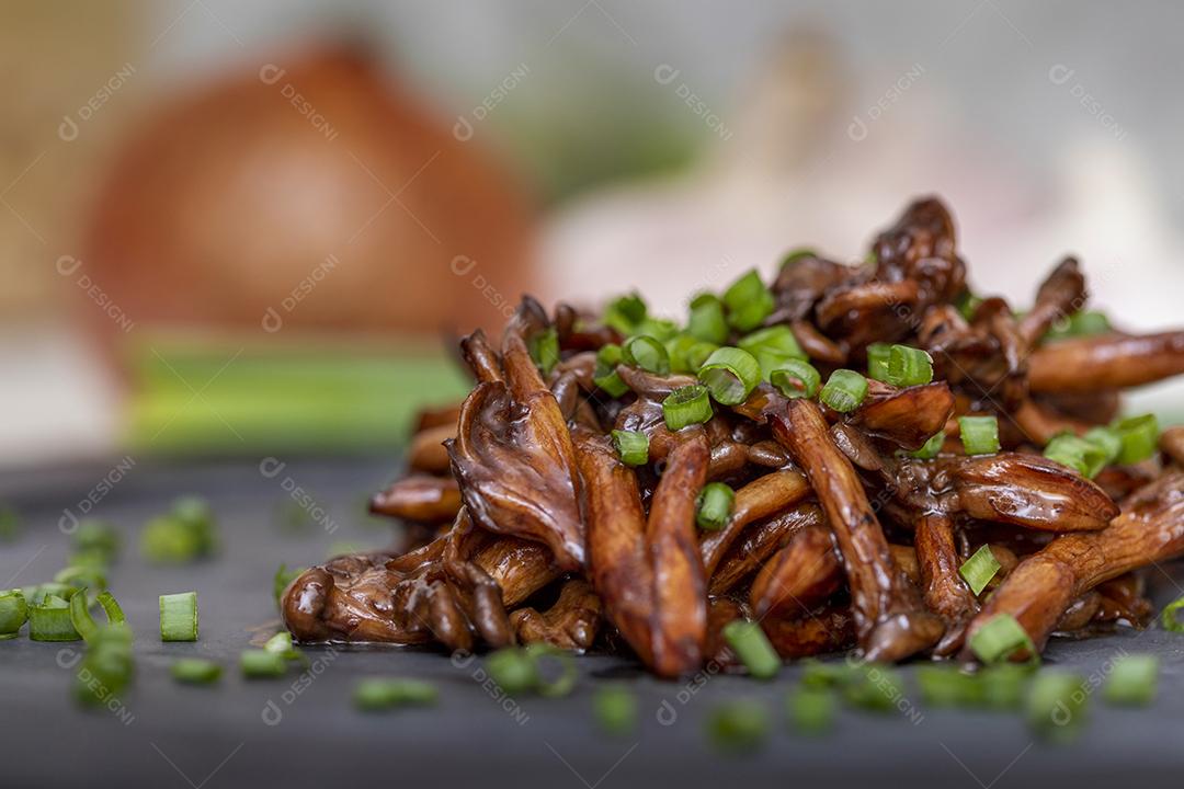 Cogumelo Shimeji servido com cebolinha no prato de pedra preta. Tipica JPG