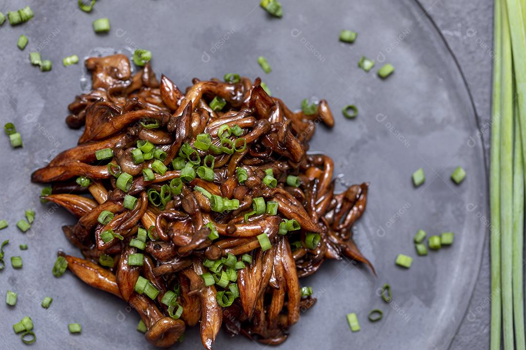 Cogumelo Shimeji servido com cebolinha no prato de pedra preta. Tipica JPG