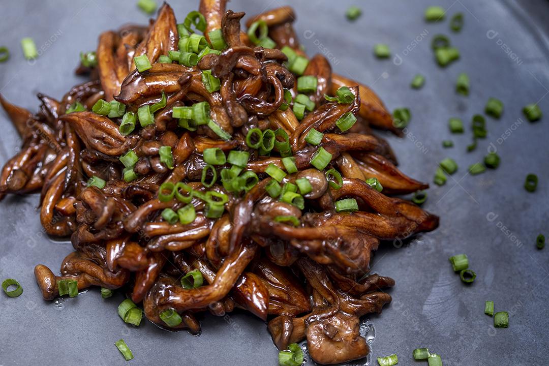 Cogumelo Shimeji servido com cebolinha no prato de pedra preta. Tipica JPG