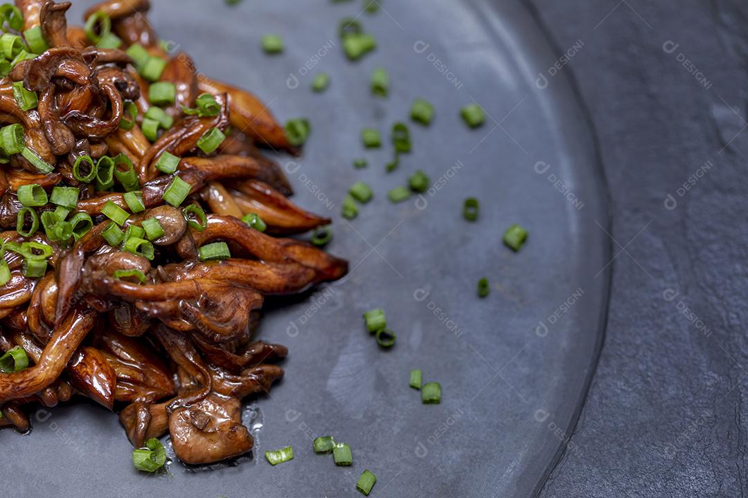 Cogumelo Shimeji servido com cebolinha no prato de pedra preta. Tipica JPG