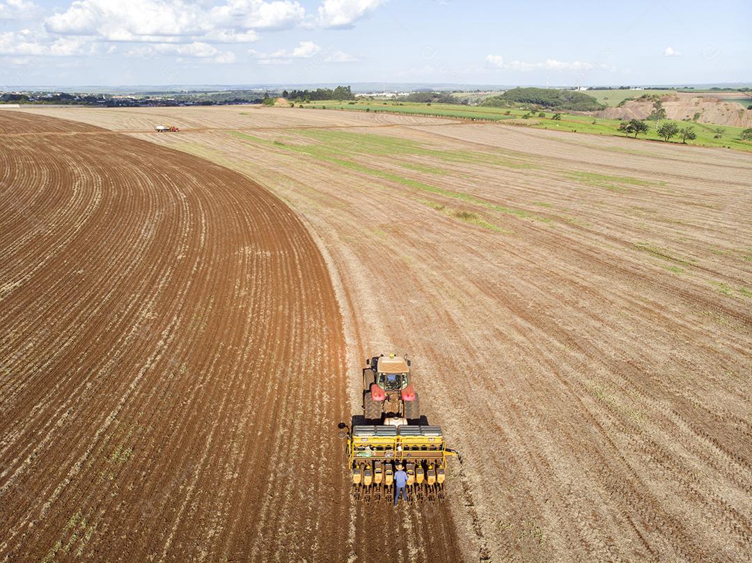 Trator com infiltrado no campo. Semeadura de milho, milho no solo JPG