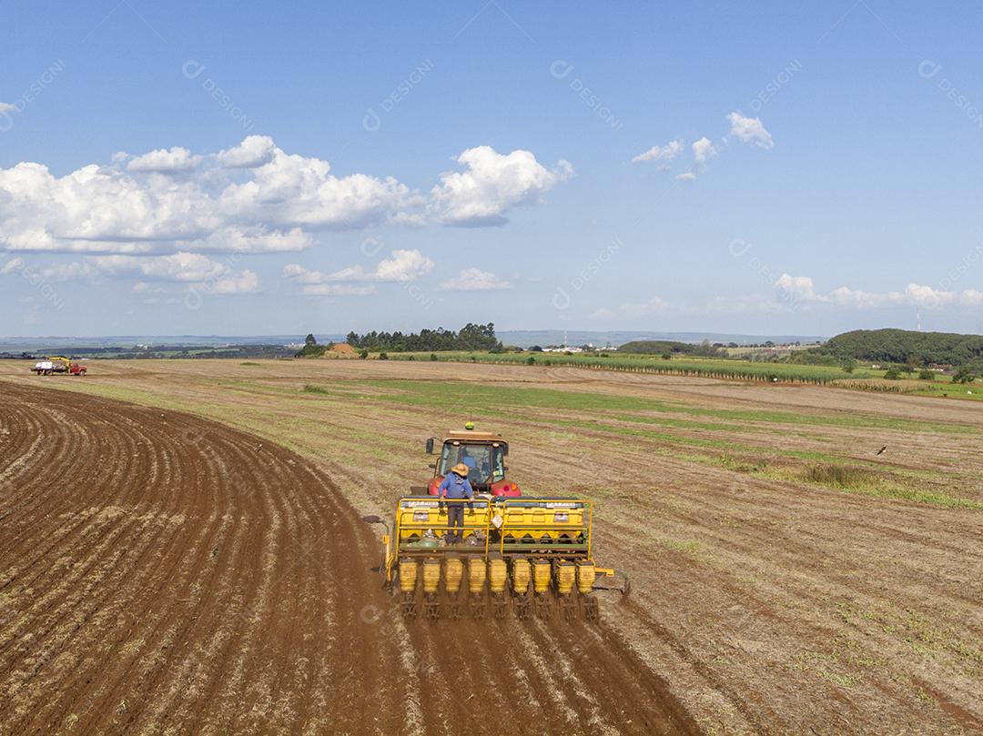 Trator com infiltrado no campo. Semeadura de milho, milho no solo JPG