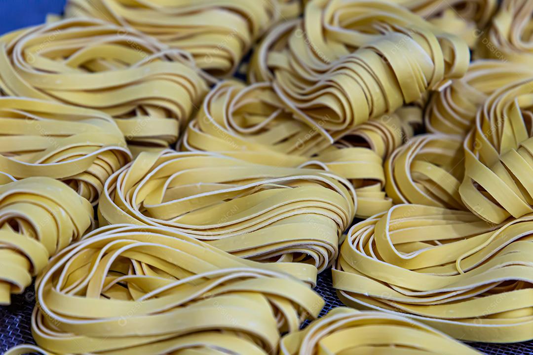 Produção artesanal de macarrão em um restaurante italiano. Macarrão amarelo no processo de secagem JPG