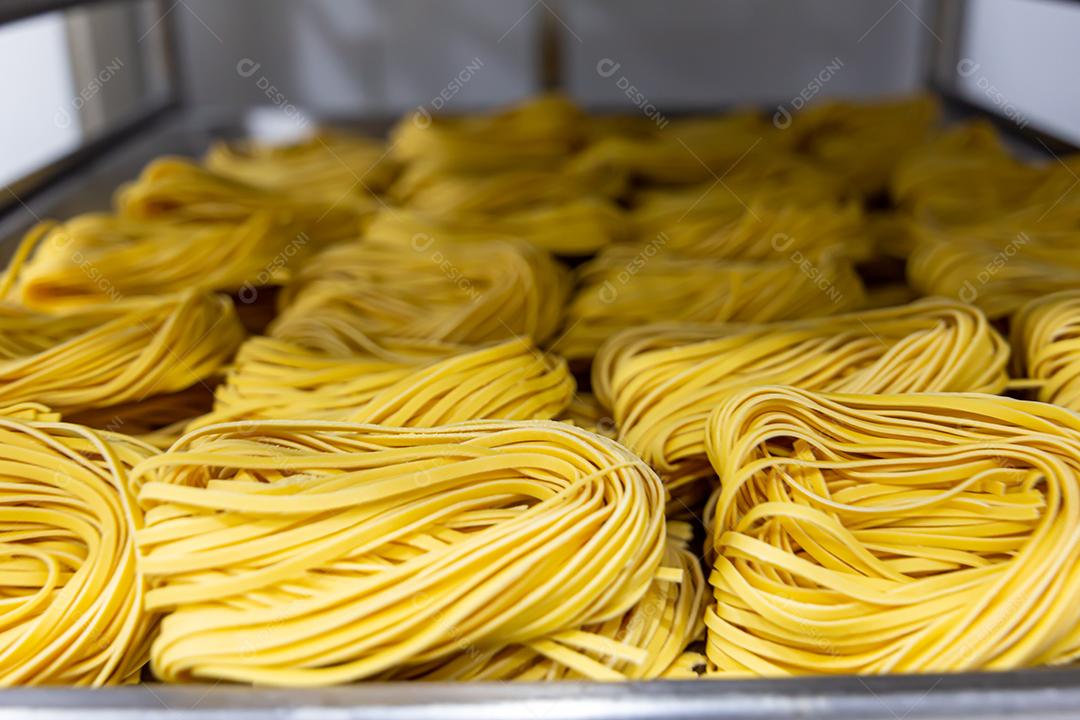 Produção artesanal de macarrão em um restaurante italiano. Macarrão amarelo no processo de secagem JPG