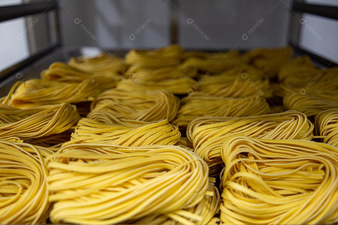 Produção artesanal de macarrão em um restaurante italiano. Macarrão amarelo no processo de secagem JPG