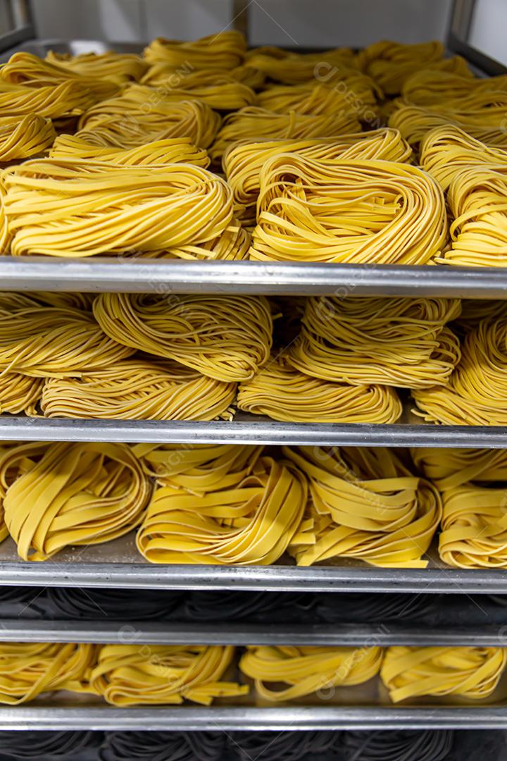 Produção artesanal de macarrão em um restaurante italiano. Macarrão amarelo no processo de secagem JPG