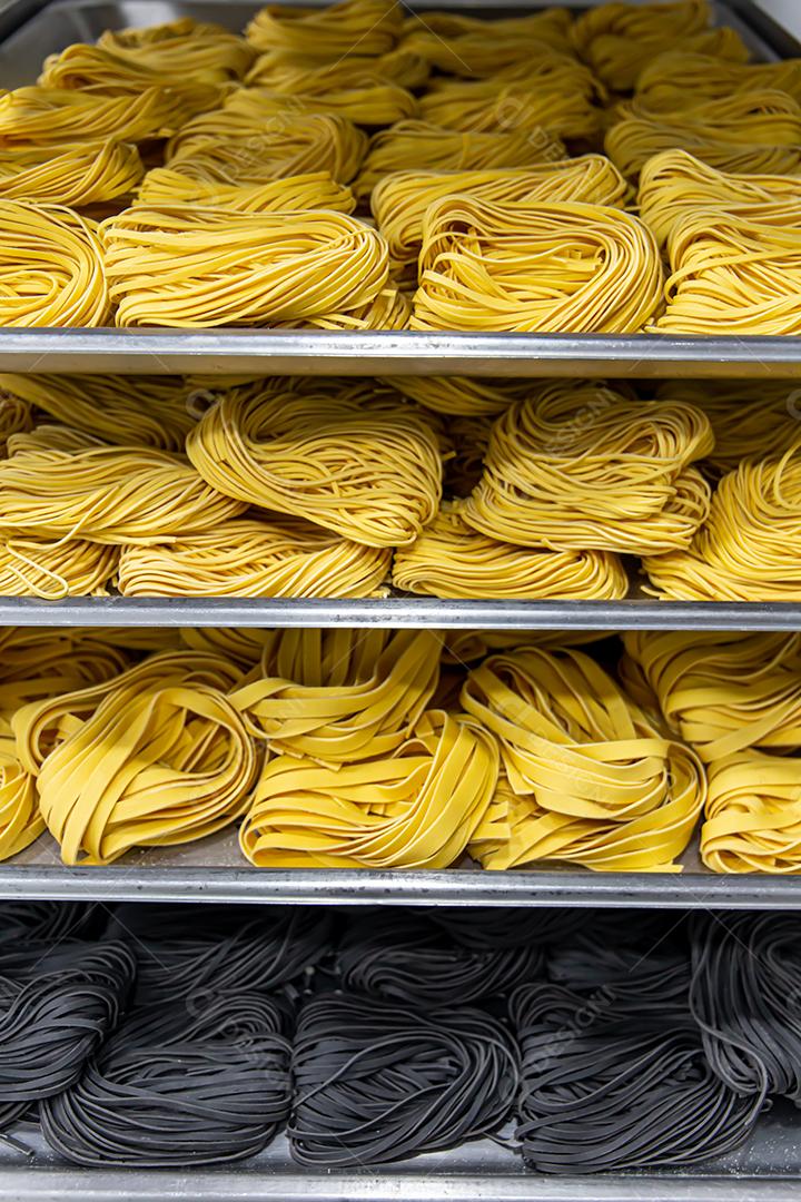 Produção artesanal de macarrão em um restaurante italiano. Macarrão amarelo no processo de secagem JPG