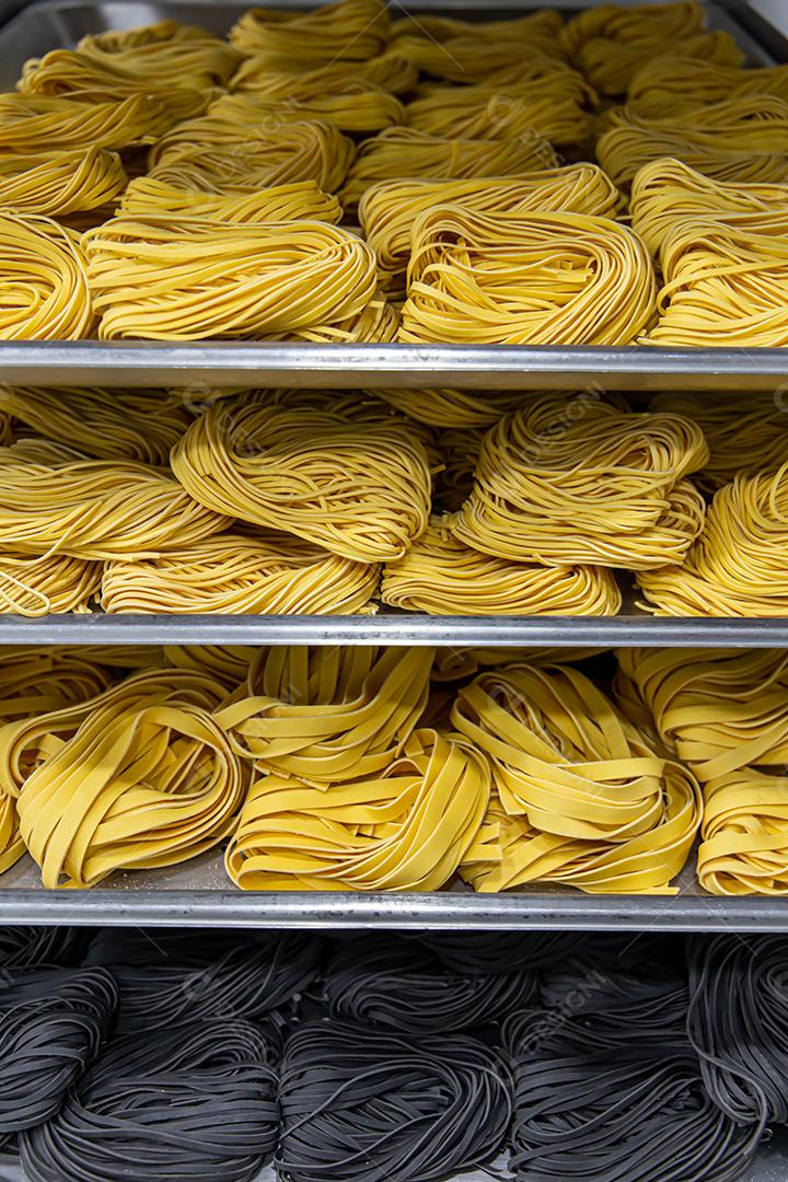 Produção artesanal de macarrão em um restaurante italiano. Macarrão amarelo no processo de secagem JPG