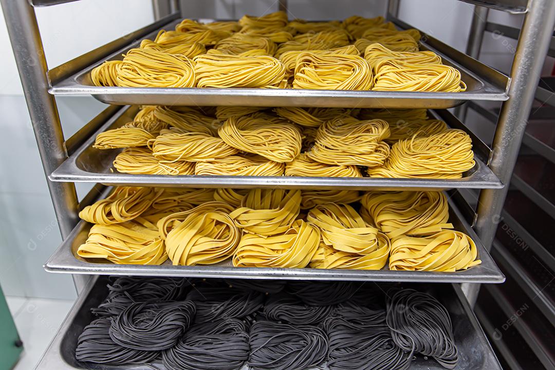 Produção artesanal de macarrão em um restaurante italiano. Macarrão amarelo no processo de secagem JPG