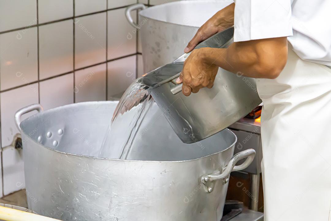 Homem cozinhando em uma cozinha de restaurante no Brasil. grandes panelas de alumínio JPG