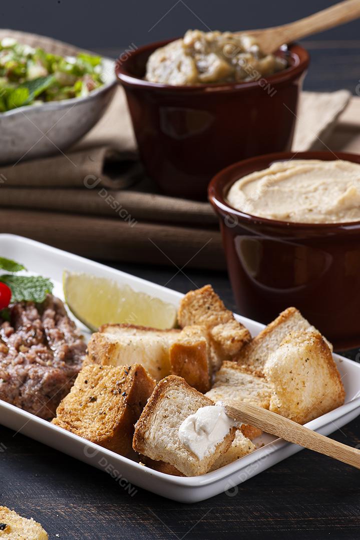 Torradas com coalhada síria, húmus e babaganush ao fundo JPG