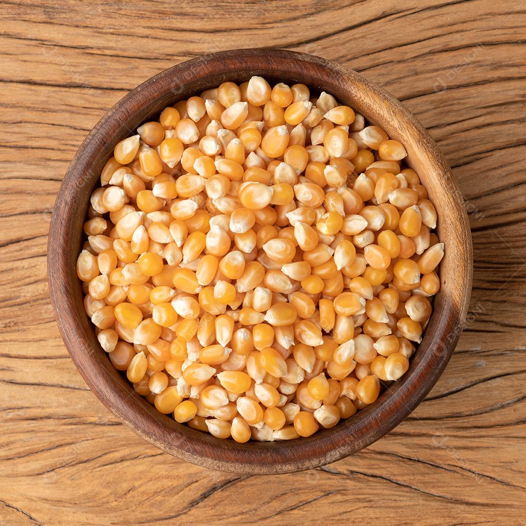 Milho seco ou grãos de pipoca em uma tigela sobre mesa de madeira JPG