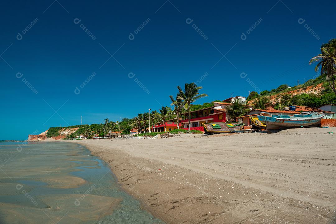 Manhã ensolarada, onde você pode ver barcos, casas e a falésia com vegetação ao fundo na Praia Redonda