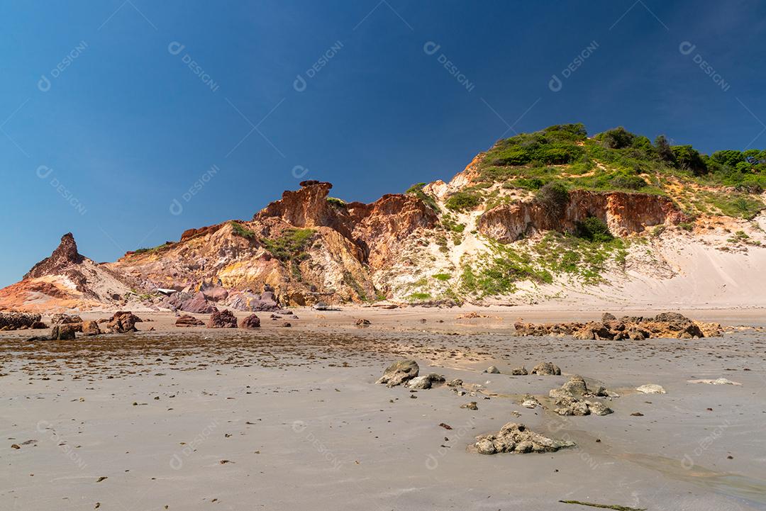 Pedras coloridas e areia na praia, ao fundo falésias vegetação natural Praia de Peroba