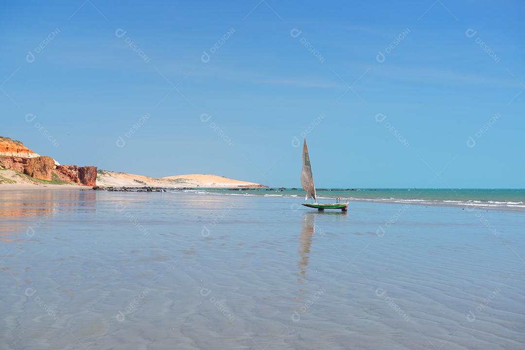 Pequenos barcos de pesca, de manhã cedo ao fundo dunas e falésias na praia de Peroba