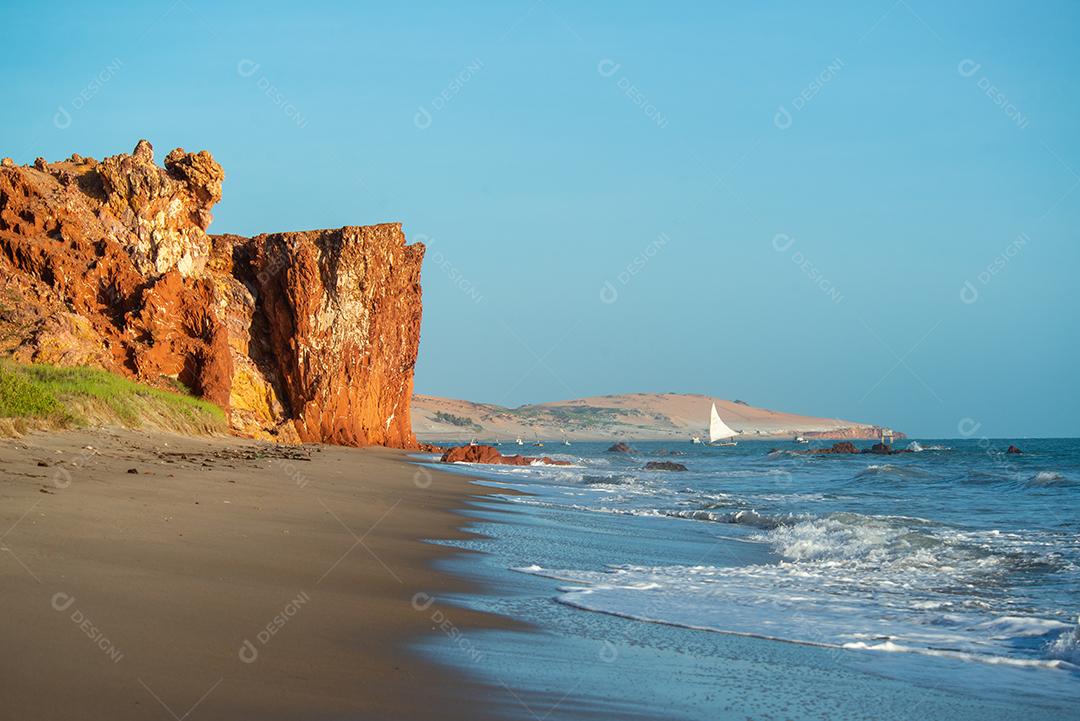 Penhascos coloridos, dunas e pequeno barco à vela de manhã cedo na praia de Peroba, Icapuí