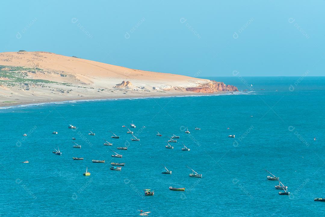 Penhascos coloridos, dunas e pequeno barco à vela de manhã cedo na praia de Peroba, Icapuí