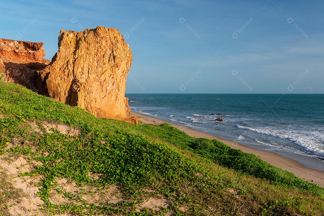 Penhascos coloridos, dunas e pequeno barco à vela de manhã cedo na praia de Peroba, Icapuí