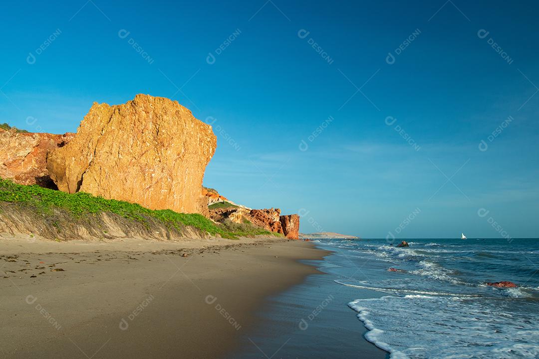 Penhascos coloridos, dunas e pequeno barco à vela de manhã cedo na praia de Peroba, Icapuí