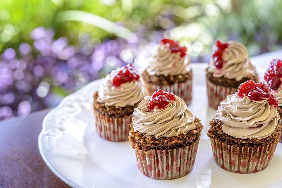 Cupcakes em chapa branca na mesa de madeira com fundo desfocado do jardim