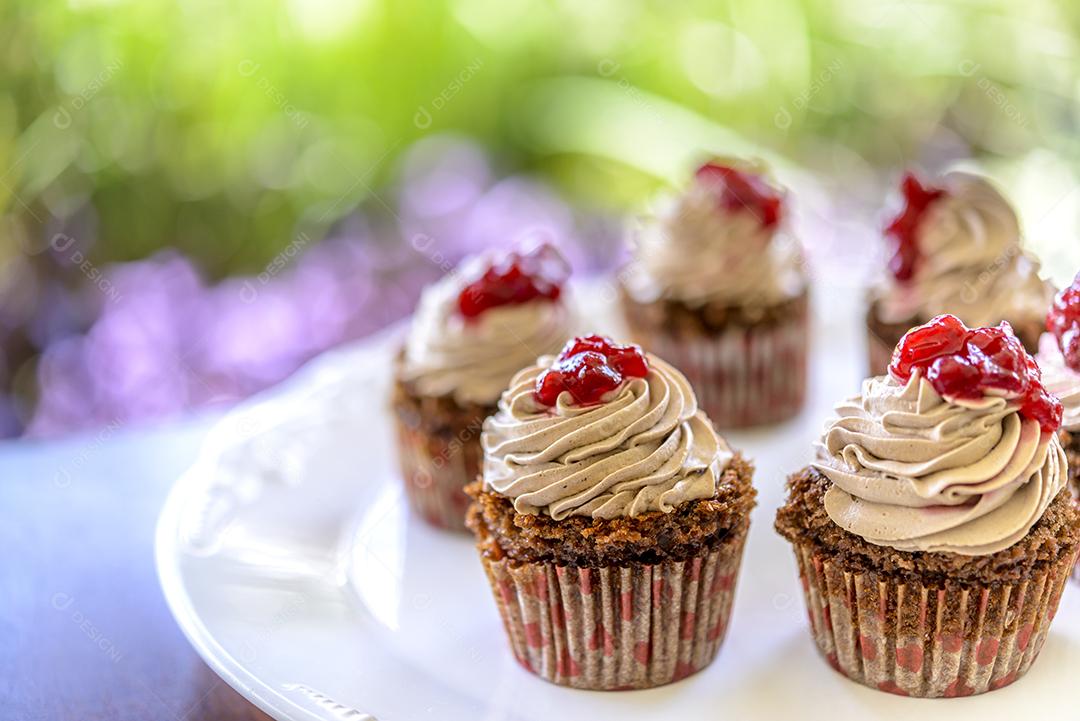 Cupcakes em chapa branca na mesa de madeira com fundo desfocado do jardim