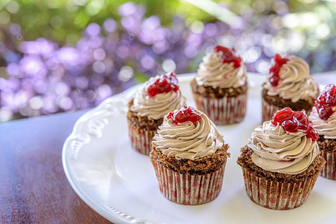Cupcakes em chapa branca na mesa de madeira com fundo desfocado do jardim