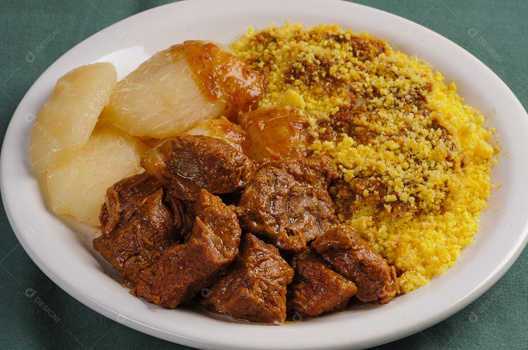 Carne estufada com cuscuz e mandioca. Culinária popular do nordeste do Brasil.