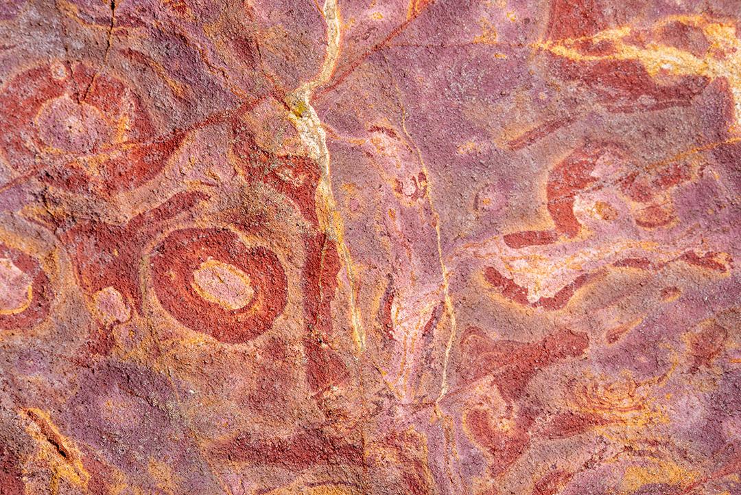 Areia colorida e rochas sedimentares, criando padrões abstratos na praia de Peroba