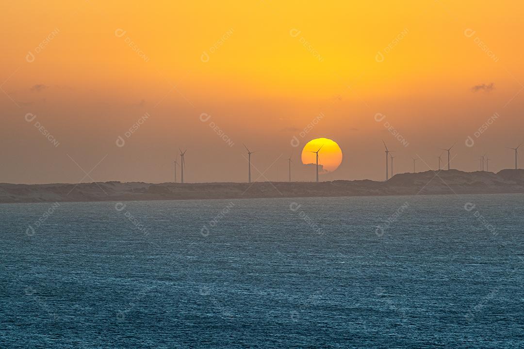 Pôr do sol atrás das torres de captação de energia eólica na praia de Ponta Grossa, Icapuí, Ceará