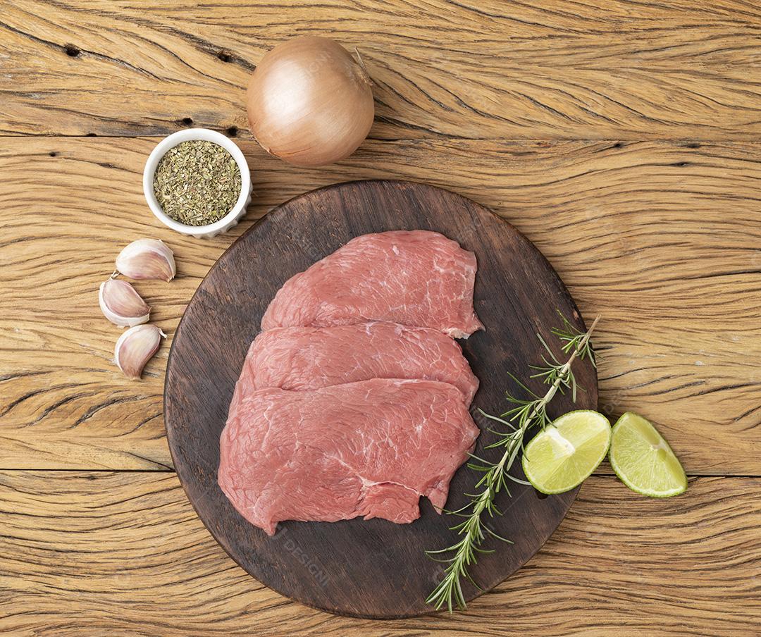 Carne de bife de alcatra sobre tábua de madeira com temperos JPG
