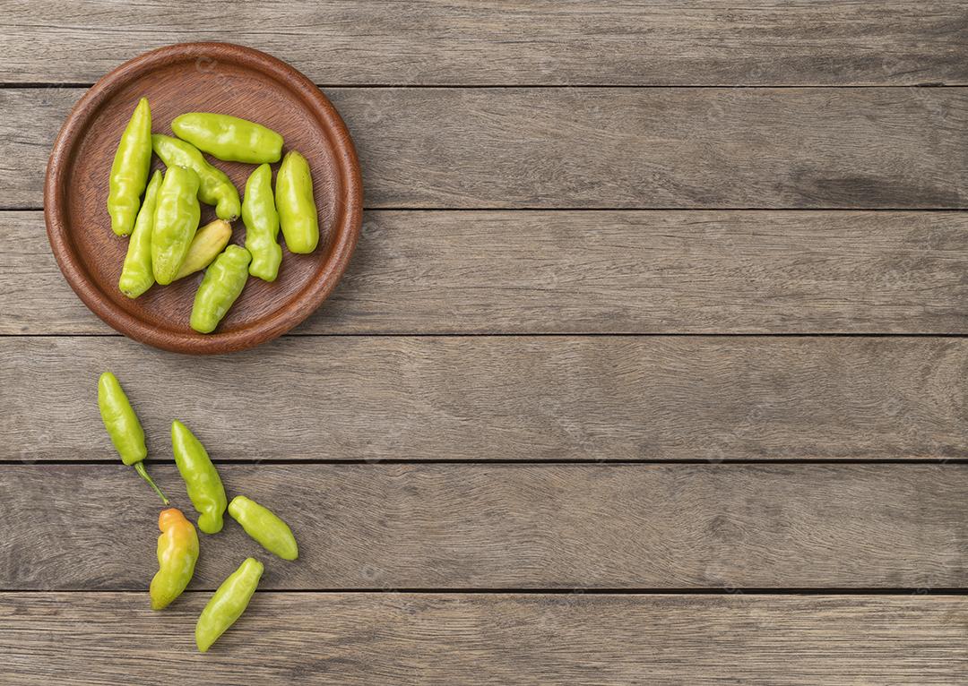 Pimentas de cheiro verde (cheiro,cheiro) em um prato sobre mesa de madeira JPG