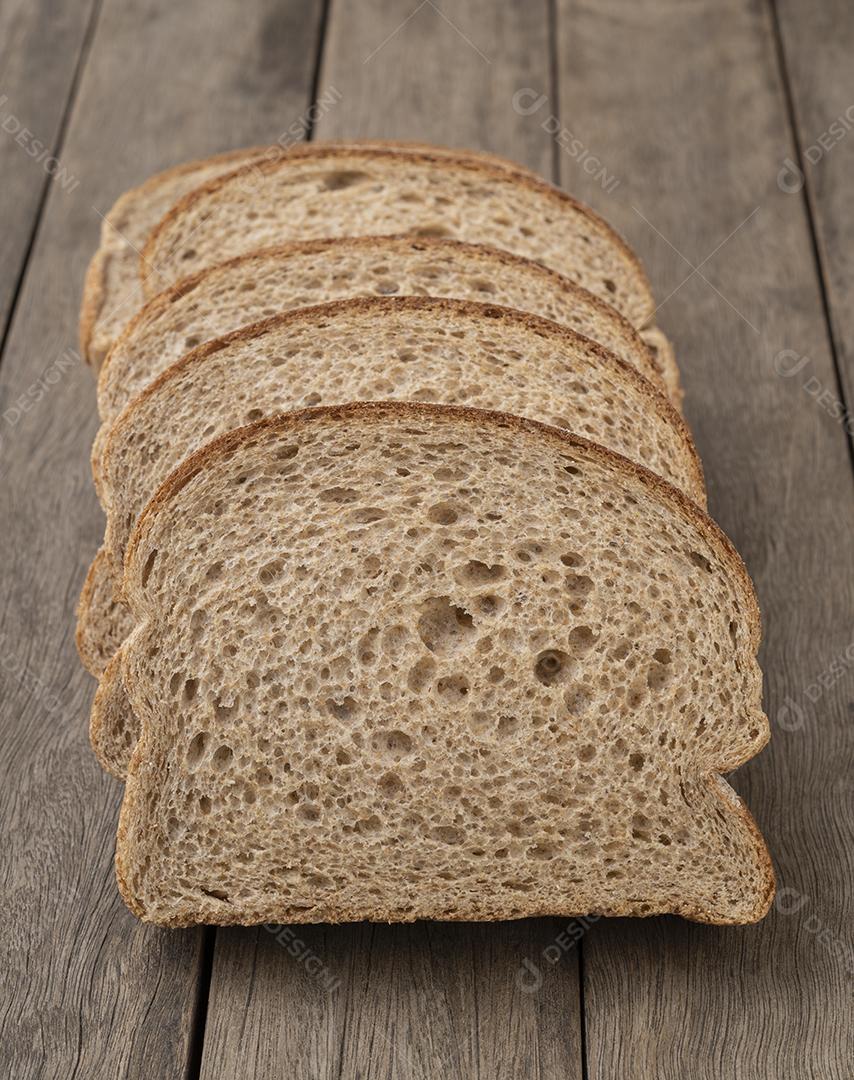 Fatias de pão de trigo inteiro sobre mesa de madeira JPG