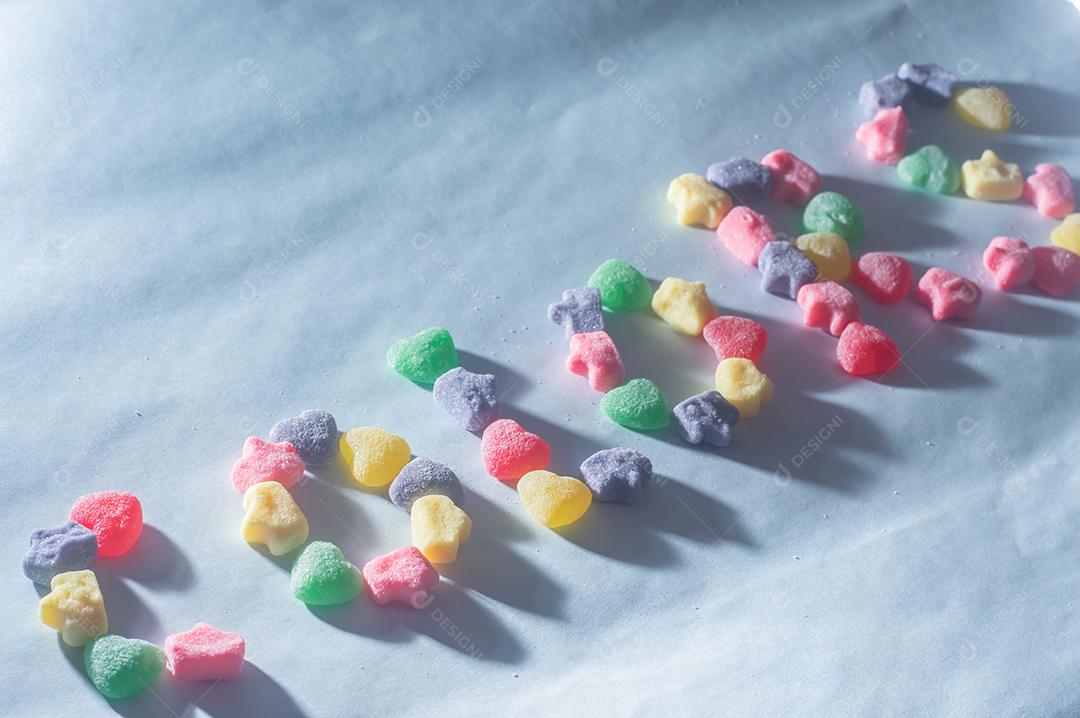 Doces coloridos variados com a palavra colors escrita, fundo azul claro