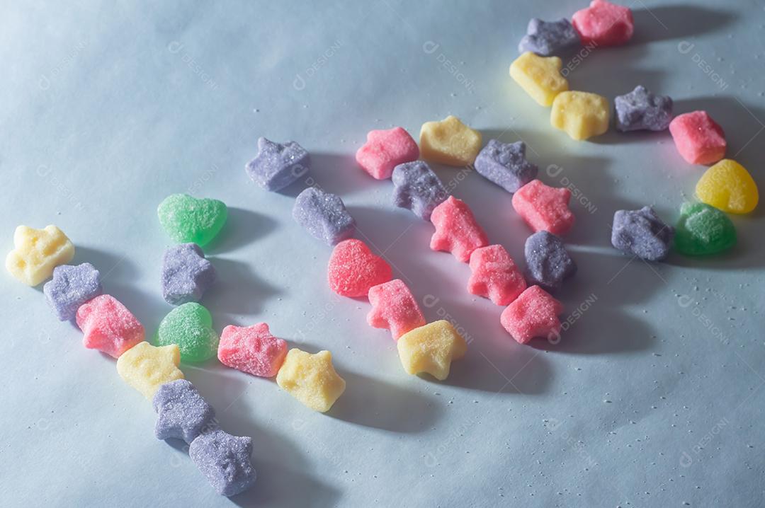 Doces coloridos variados com a palavra kids escrita, fundo azul claro