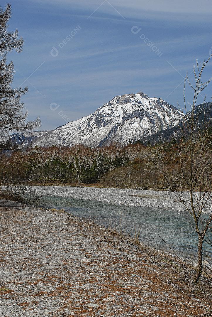 Montanhas cobertas de neve ao fundo e lago claro na cena de inverno em Kamikochi, Japão