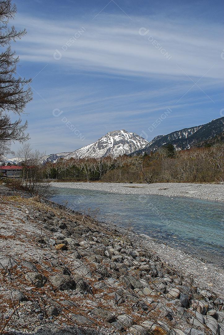 Montanhas cobertas de neve ao fundo e lago claro na cena de inverno em Kamikochi, Japão